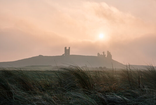 Sunrise Over Dunstanburgh Castle. Northumberland, UK.