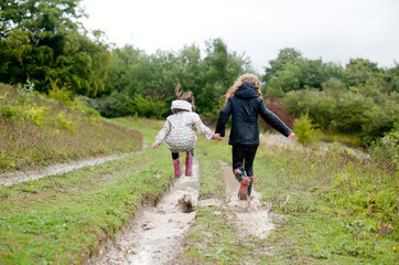 Sisters walking and jumping through a muddy puddle