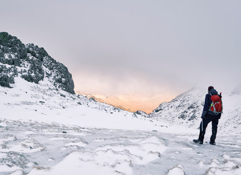 Winter mountaineer using Ice Axe and crampons below Great End. Esk Hause, Cumbria, UK.