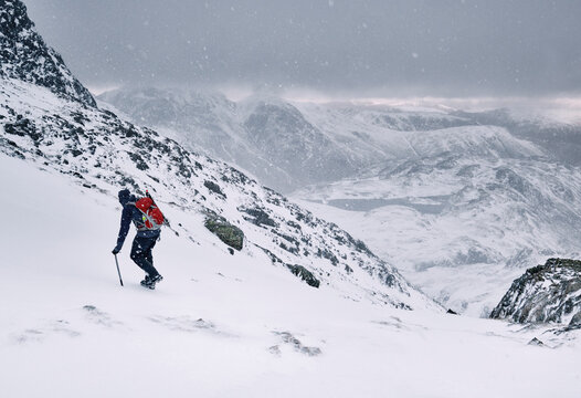 Winter mountaineer using Ice Axe and crampons below Great End. Esk Hause, Cumbria, UK.