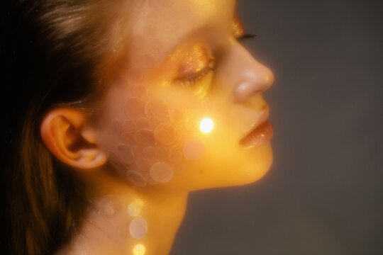 Young woman with glitter makeup in golden light