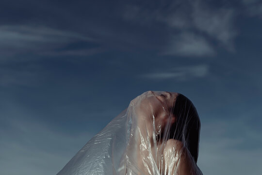 Woman in nature covered with plastic. Plastic problem