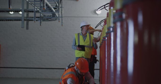 Mature inspector checking workers near fire extinguishers