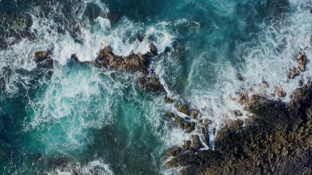 Top down aerial view of ocean waves crashing