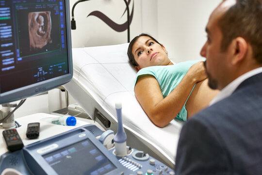 obstetrician doctor doing an ultrasound exam of a pregnant woman