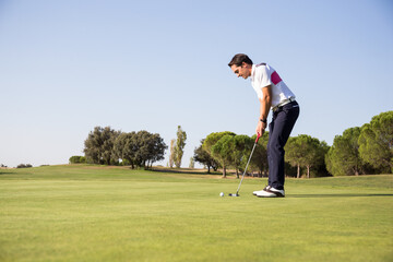 Golfer carefully preparing to hit ball