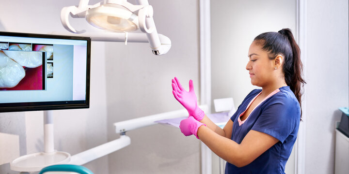 Young dental doctor preparing for a procedure taking on her gloves