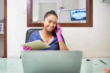 Smiling dentist receiveing a call in her office
