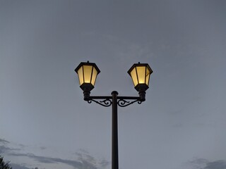 turned on lamp in the park in the evening against the sky