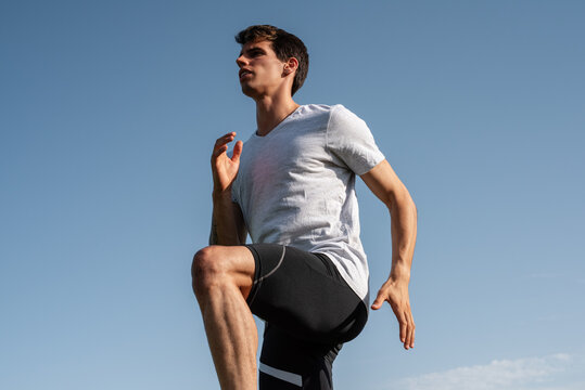Young sportsman exercising against blue sky