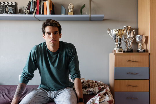 Young sportsman sitting on bed at home