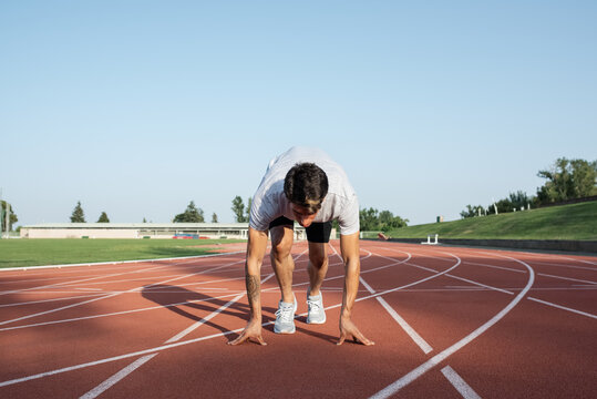 Young runner in crouch start position on racetrack