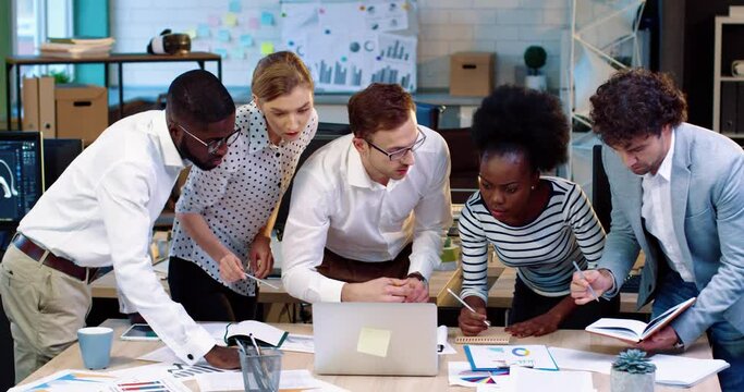 Young senior project manager in white shirt and glasses entrusts the task to subordinates. Work in office. Distribution of responsibilities.