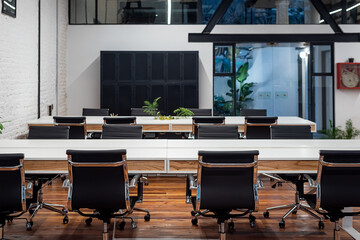 Chairs lined up at table in empty coworking space