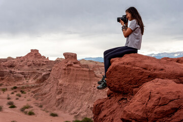 Woman photographer taking pictures of red earth formations