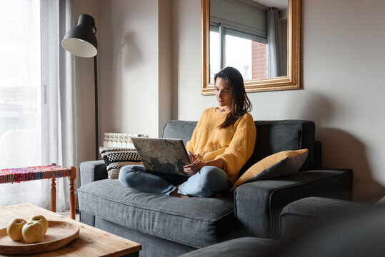 Woman using laptop on sofa at home