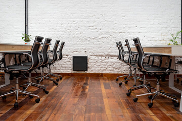 Chairs lined up at table in empty coworking space