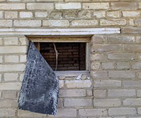 one broken out small window of an old brick building