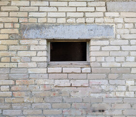 one broken out small window of an old brick building