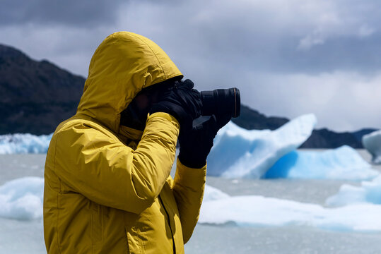 Photographer with a yellow jacket surrounded by some ice floes in Grey Lake, Patagonia, Chile