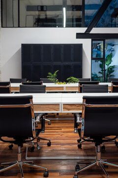 Chairs lined up at table in empty coworking space