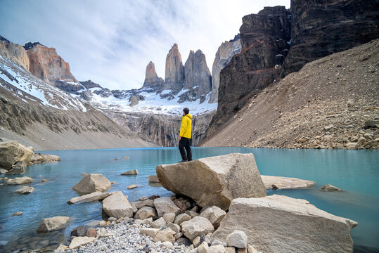 Hiker gazing the views of a blue lagoon in the base of the Towers in Torres del Paine National Park, Chile