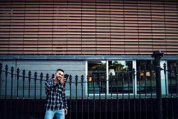 Chico joven con camisa de cuadros posando con smartphone