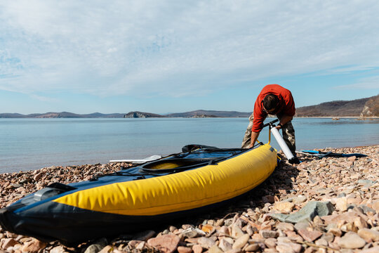Adult male finishing to pump boat near sea