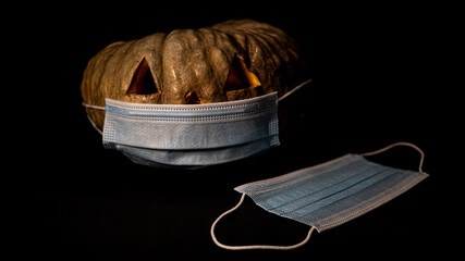 A closeup shot of a Halloween pumpkin with sanitary mask - concept of the new normal