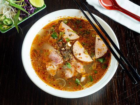 Bowl of Pho on Wooden Table with Chopsticks and Napkin