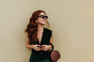 Ginger woman in sunglasses holds handbag