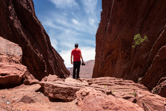 Photographer standing on a rock with a camera taking suroounded by red earth formations
