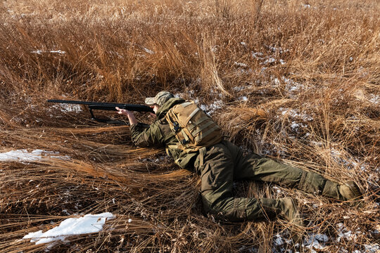 Man lying on grass during hunt in field