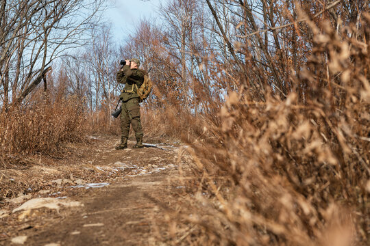 Huntsman standing on path and using binoculars