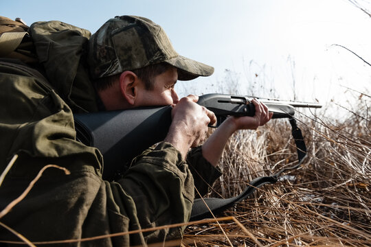 Focused huntsman firing gun in grass