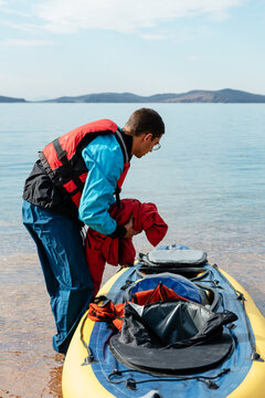 Man in life jacket putting belongings in boat
