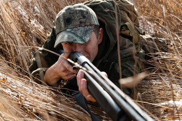 Hunter lying in grass and shooting