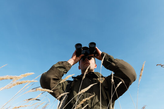 Guy in camouflage looking at distance against blue sky