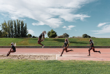 Stages of black sportswoman jumping into sandpit