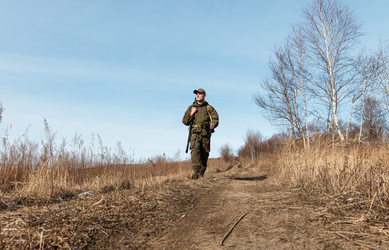 Confident hunter walking on countryside road against sky