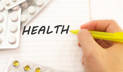 Text health on white background. There are various pills and vitamins around. Medical concept