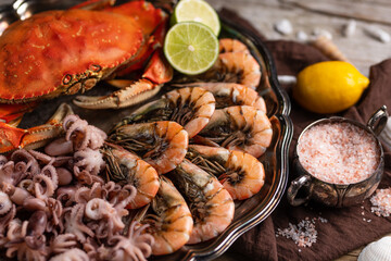Close-up of big round dish with king crab, shrimps and octopuses served with lime, lemon and sea salt. Brown napkin background. Seafood concept. Healthy meal. Traditional Thai recipe.