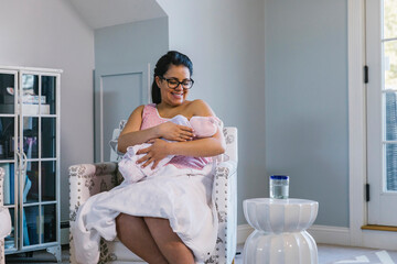Pregnant Hispanic Mother Breast feeding Newborn Child at Home