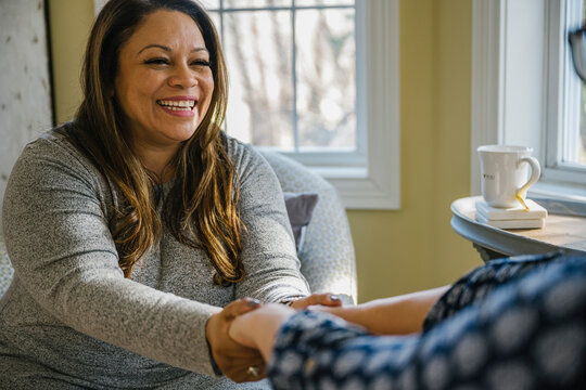 Hispanic Doula Holding Hands with Expectant Mother at Home