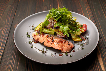 Salad with avocado and salmon, on a wooden background