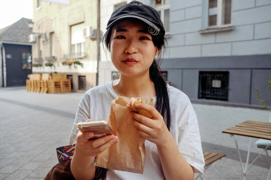 Young Woman Eating Baked Good On The Street