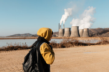 Ethnic man walking near pond and factory