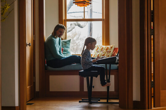 Young Child Playing Piano while Mother Looks on and Smiles