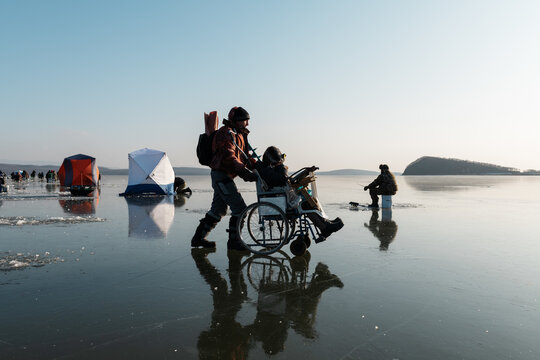 Angler with friend with disability walking on ice
