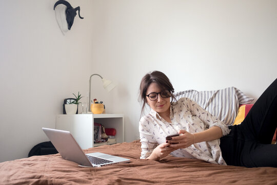 Portrait of a young female model laying on the bed and using laptop